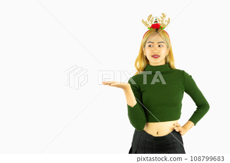 young asian woman wears a reindeer headband for christmas concept poiting hand isolated on white background 108799683