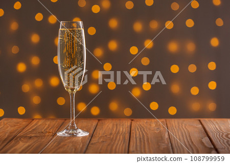 Glasses with champagne on a wooden background against a bokeh background of lights 108799959