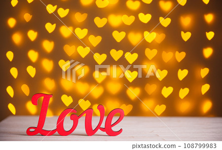 the inscription Love on a wooden background with beautiful hearts made of lights on a blurred background the inscription Love on a wooden background with beautiful hearts made of lights on a blurred background 108799983