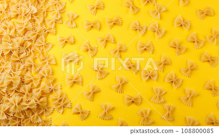Different types and shapes of dry italian pasta on a yellow background 108800085
