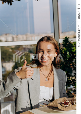 Happy attractive woman is enjoying tasty dessert in restaurant during lunch with friends Happy attractive woman is enjoying tasty dessert in restaurant during lunch with friends 108800185