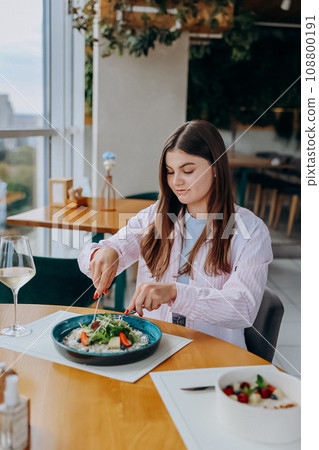 Young attractive woman enjoys tasty meal on cafe or restaurant background 108800191