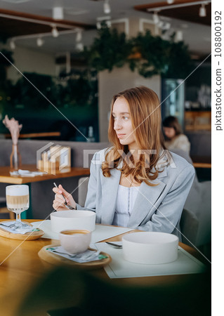 Young attractive woman enjoys tasty meal on cafe or restaurant background 108800192