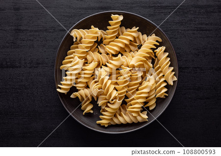 Uncooked fusilli pasta. Uncooked italian pasta on plate. Top view. Uncooked fusilli pasta. Uncooked italian pasta on plate. Top view. 108800593