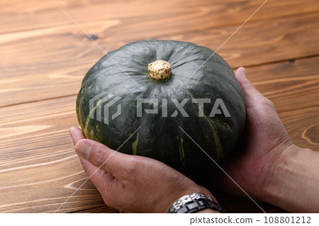 雙手握著南瓜,木紋背景 雙手握著南瓜,木紋背景 108801212