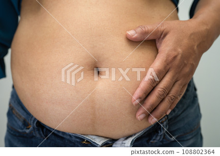 Overweight Asian woman show and use hand to squeeze fat belly. 108802364