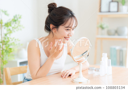 Young woman doing skin care in the living room Young woman doing skin care in the living room 108803134