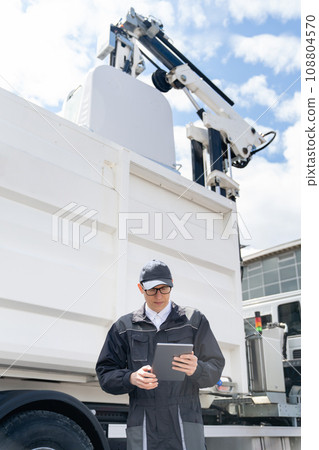 Manager with a digital tablet next to garbage truck Manager with a digital tablet next to garbage truck 108804570