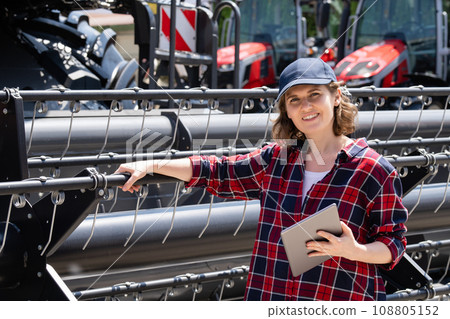 Woman farmer with digital tablet on a background of harvester. Smart farming concept 108805152