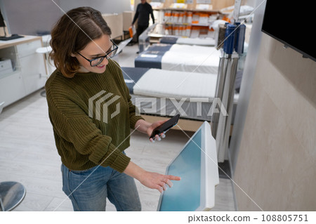Woman with phone uses self-service kiosk in the shopping mall Woman with phone uses self-service kiosk in the shopping mall 108805751