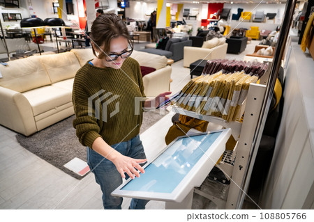 Woman with phone uses self-service kiosk in the shopping mall Woman with phone uses self-service kiosk in the shopping mall 108805766