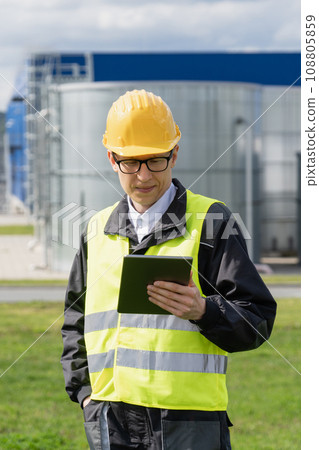 Engineer with digital tablet on a background of gas tanks Engineer with digital tablet on a background of gas tanks 108805859