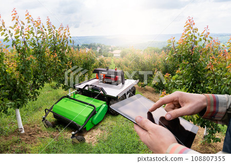 Farmer with digital tablet controls autonomous lawnmower 108807355