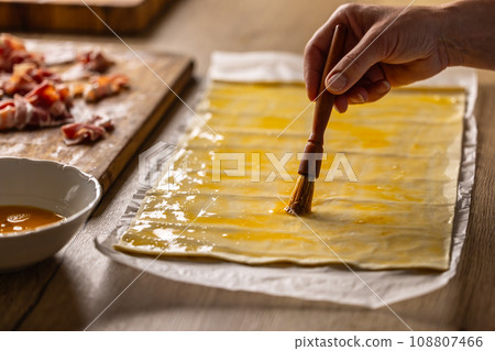 A female cook brushes puff pastry with egg 108807466