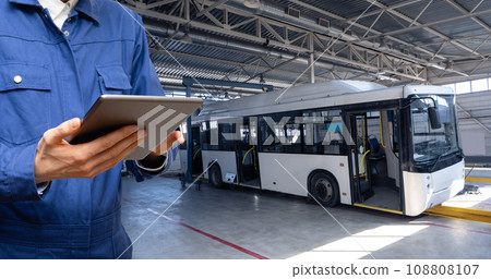 Serviceman with digital tablet on the background of the bus in the garage Serviceman with digital tablet on the background of the bus in the garage 108808107