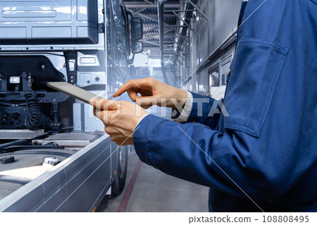 Serviceman with digital tablet on the background of the truck in the garage. Serviceman with digital tablet on the background of the truck in the garage. 108808495