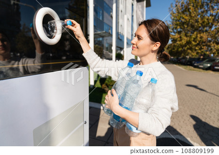 Woman uses a self service machine to receive used plastic bottles 108809199