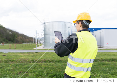 Engineer with digital tablet on a background of gas tanks Engineer with digital tablet on a background of gas tanks 108809201