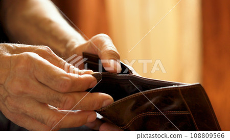 An elderly man's hands, covered with knotted veins, search for coins in his wallet An elderly man's hands, covered with knotted veins, search for coins in his wallet 108809566