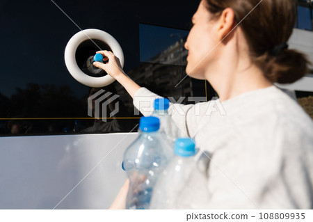 Woman uses a self service machine to receive used plastic bottles 108809935