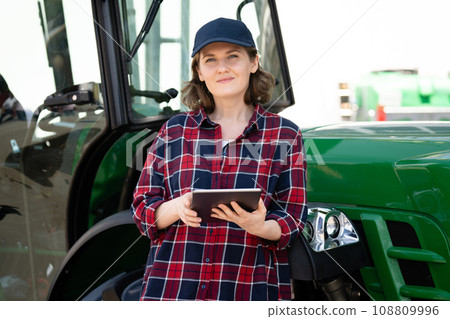Woman farmer with agricultural tractor. 108809996
