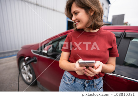 Woman charging red electric car. Woman charging red electric car. 108810351