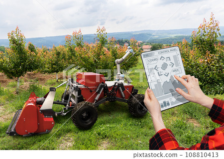 Farmer controls autonomous robot in a fruit garden. 108810413