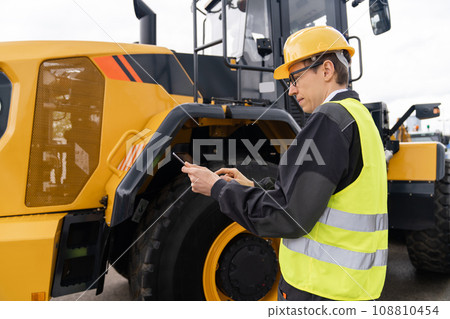 Worker in a helmet with a digital tablet Worker in a helmet with a digital tablet 108810454