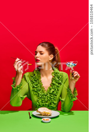Portrait of gorgeous woman, lady eating meal, drinking cocktail of tablets, pills and vitamins isolated red background. 108810464