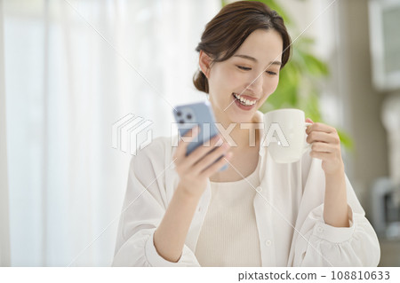 A woman looking at her smartphone in the living room A woman looking at her smartphone in the living room 108810633