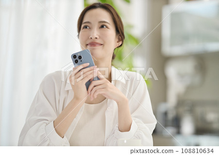 A woman looking at her smartphone in the living room A woman looking at her smartphone in the living room 108810634
