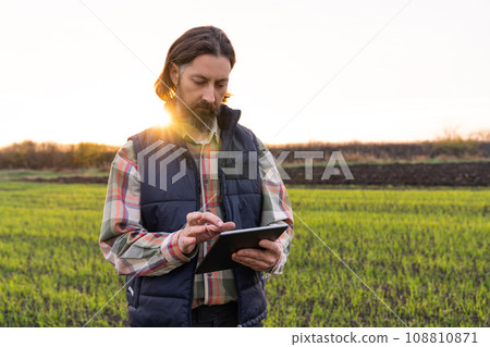 Farmer with digital tablet in young wheat field. Farmer with digital tablet in young wheat field. 108810871