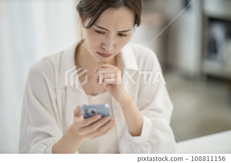 A woman looking at her smartphone in the living room A woman looking at her smartphone in the living room 108811156