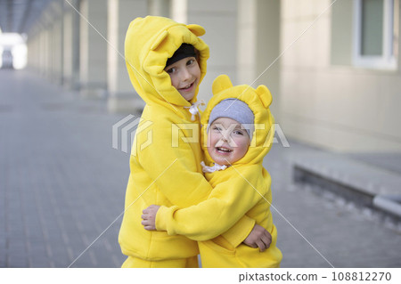 Little brother and sister. Funny children boy and girl in yellow suits hug each other. 108812270