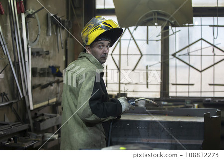 A welder works with metal in a factory shop. A welder works with metal in a factory shop. 108812273