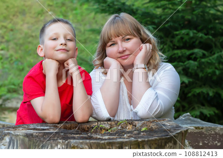 Happy mom and son on a summer walk look at the camera smiling. Happy mom and son on a summer walk look at the camera smiling. 108812413