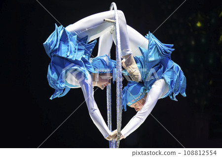 Two acrobat girls show a circus number on a dark background. Acrobatic performance. 108812554