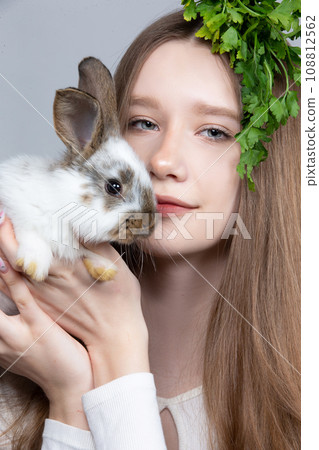 Portrait of a rural girl with a bunch of parsley on her head and a rabbit. Portrait of a rural girl with a bunch of parsley on her head and a rabbit. 108812562