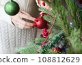 Female hands with red manicure and gold foil on the nails. Winter and Christmas time concept. Manicured woman's hands with Christmas decoration. 108812629