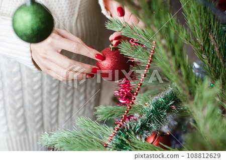 Female hands with red manicure and gold foil on the nails. Winter and Christmas time concept. Manicured woman's hands with Christmas decoration. Female hands with red manicure and gold foil on the nails. Winter and Christmas time concept. Manicured woman's hands with Christmas decoration. 108812629