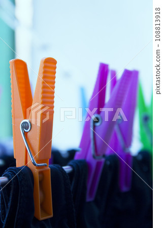 Clothespins holding clothes on clothesline. Various colors. 108813918