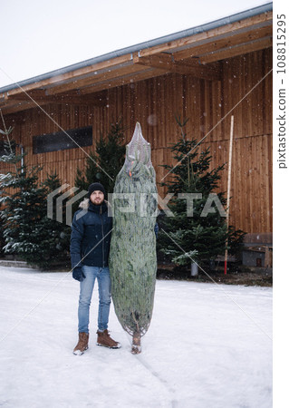 Young man stand by Christmas tree. Big tree for big family. Happy winter holidays Young man stand by Christmas tree. Big tree for big family. Happy winter holidays 108815295