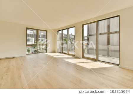 an empty living room with wood flooring and sliding glass doors looking out onto the street in front of the house an empty living room with wood flooring and sliding glass doors looking out onto the street in front of the house 108815674