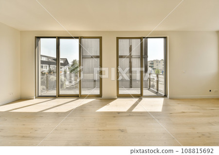 an empty living room with sliding glass doors and hardwood flooring in the middle part of the room is white an empty living room with sliding glass doors and hardwood flooring in the middle part of the room is white 108815692