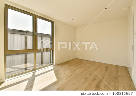 an empty room with wood flooring and sliding glass doors that open to the outside, looking out onto the street an empty room with wood flooring and sliding glass doors that open to the outside, looking out onto the street 108815697