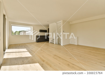 an empty living room with wood flooring and white walls in the room is very light, bright and clean 108815764