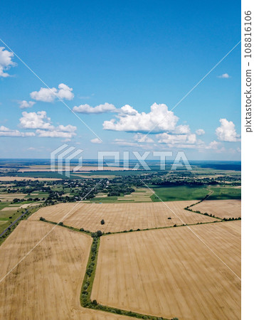 Beautiful agricultural landscape, open field with blue sky and white clouds. Farmfields from a bird's eye view. Beautiful agricultural landscape, open field with blue sky and white clouds. Farmfields from a bird's eye view. 108816106