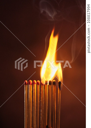 a row of matches are lit on a dark background a row of matches are lit on a dark background 108817994