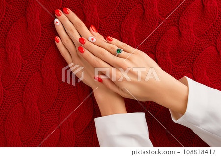 Manicured womans hands on knitted wool red fabric. Fashionable valentines day nail design Manicured womans hands on knitted wool red fabric. Fashionable valentines day nail design 108818412