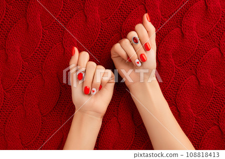 Manicured womans hands on knitted wool red fabric. Fashionable valentines day nail design Manicured womans hands on knitted wool red fabric. Fashionable valentines day nail design 108818413